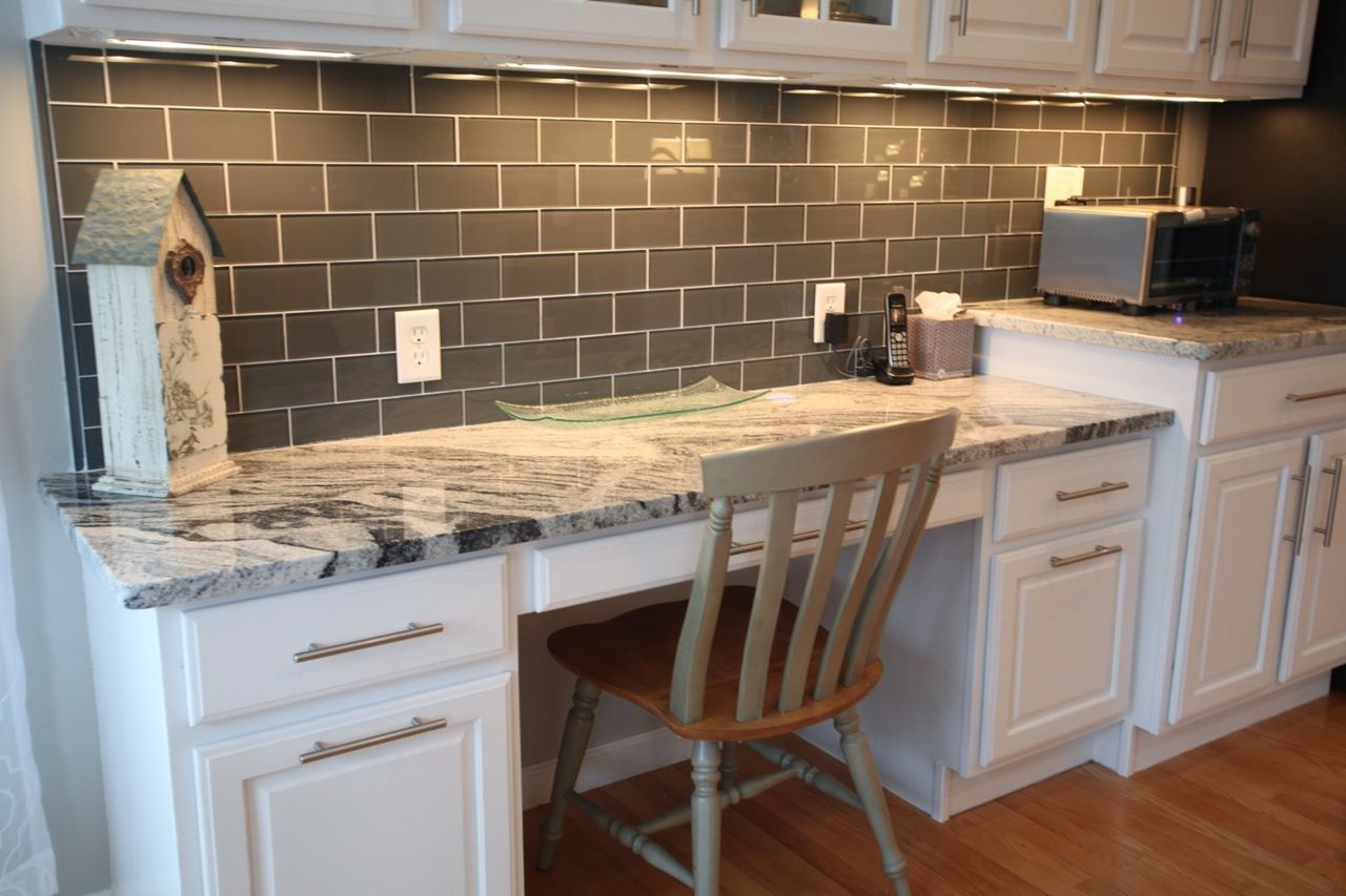 A kitchen with a desk and a chair in it.