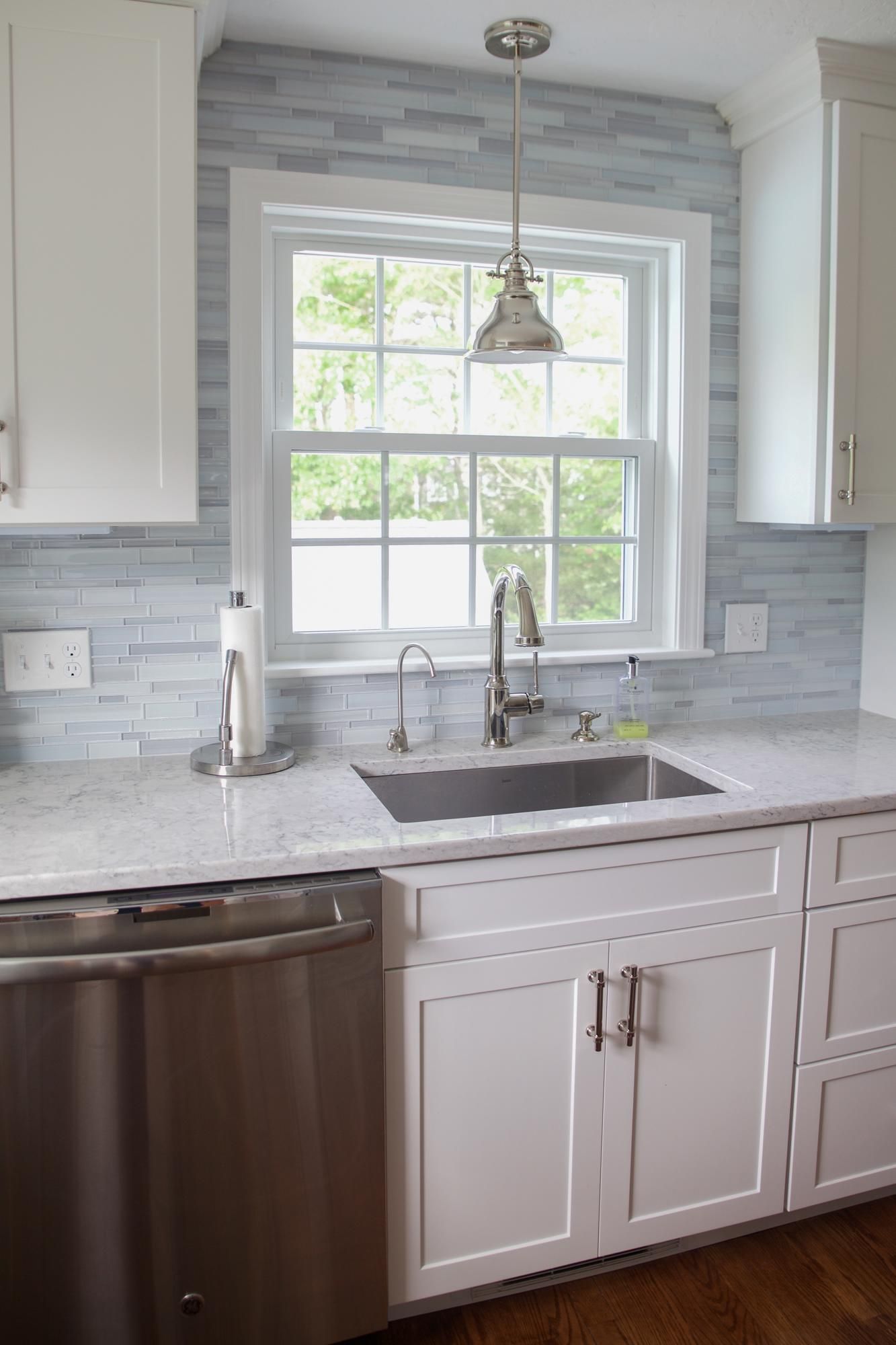 A kitchen with white cabinets and a stainless steel dishwasher