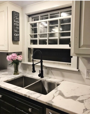 A kitchen with a sink and a window with a sign that says cat on it.