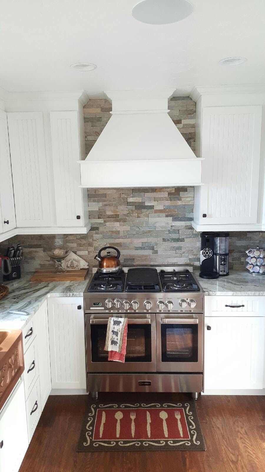 A kitchen with a stove and a rug on the floor.