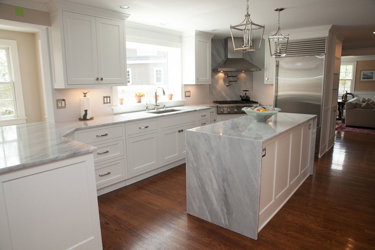 A kitchen with white cabinets and marble counter tops