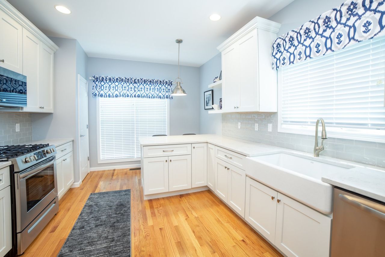 A kitchen with white cabinets , stainless steel appliances , and hardwood floors.