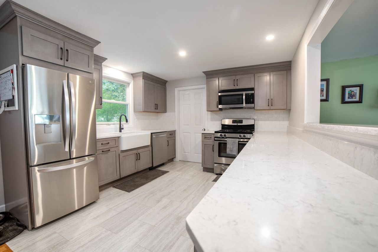 A kitchen with stainless steel appliances and gray cabinets.