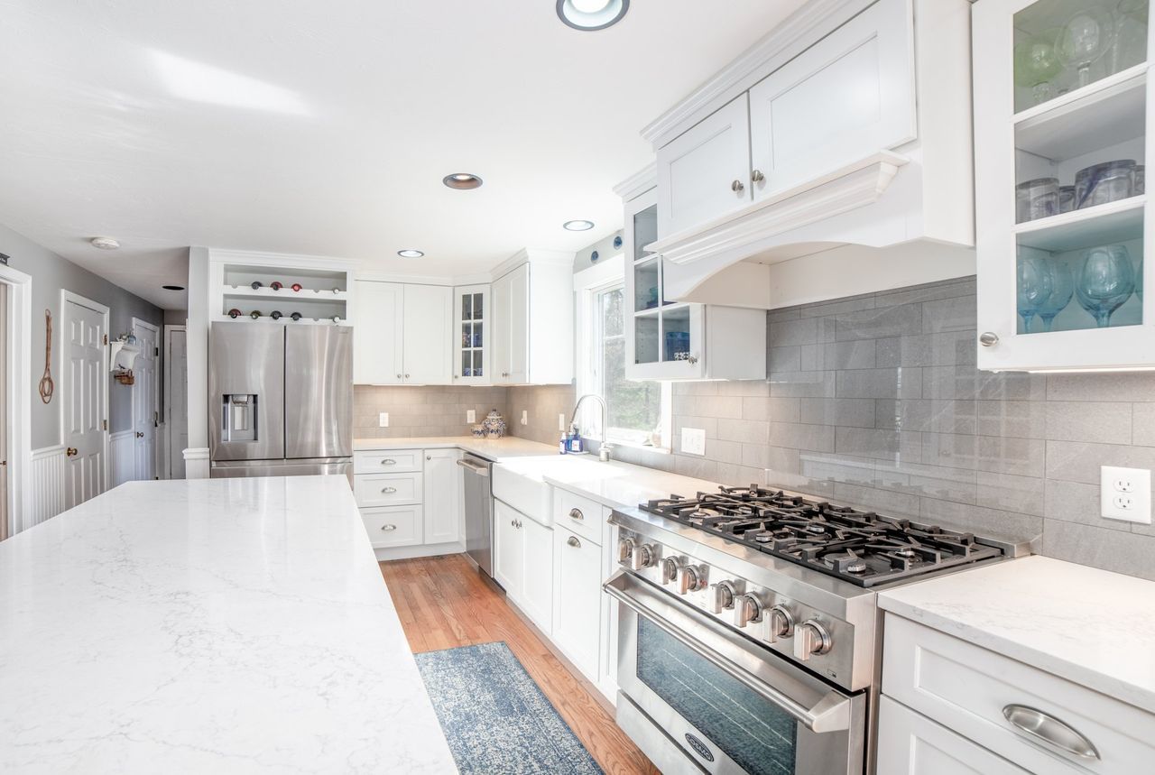 A kitchen with white cabinets , stainless steel appliances , and a large island.