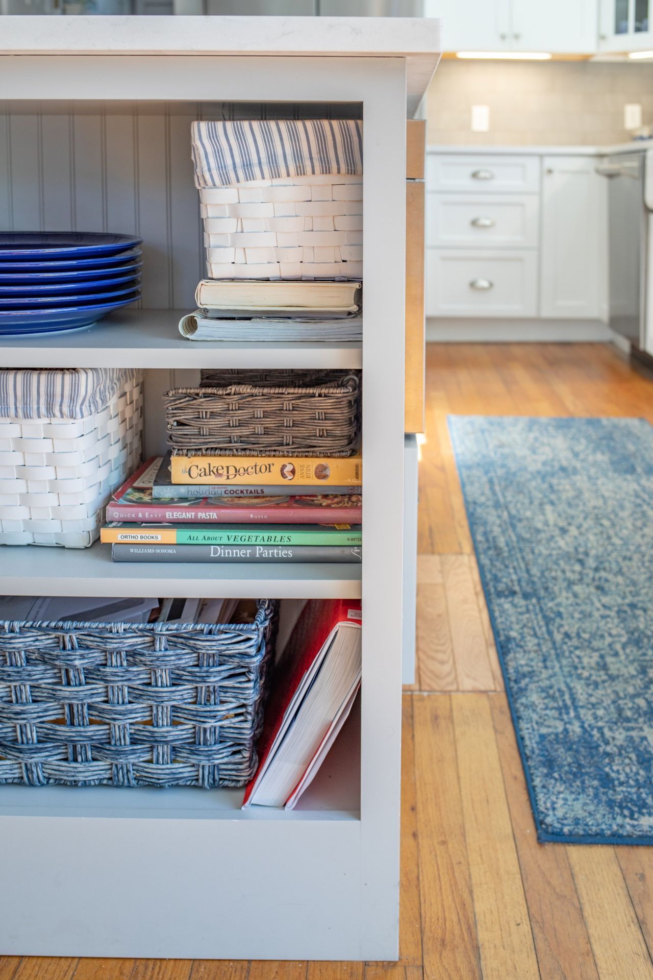 A kitchen with a shelf filled with books and baskets.