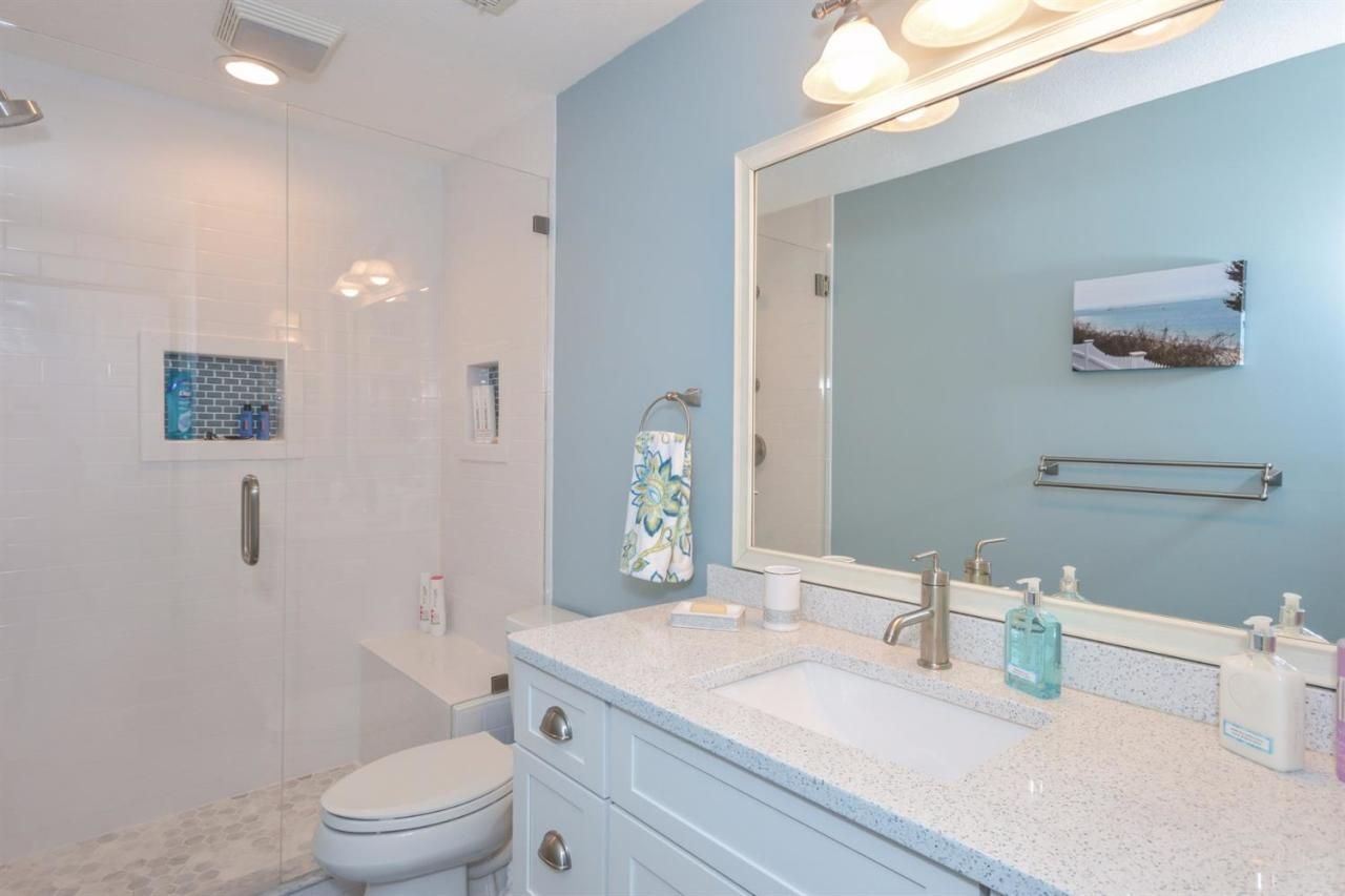 A bathroom with a toilet , sink , mirror and shower.