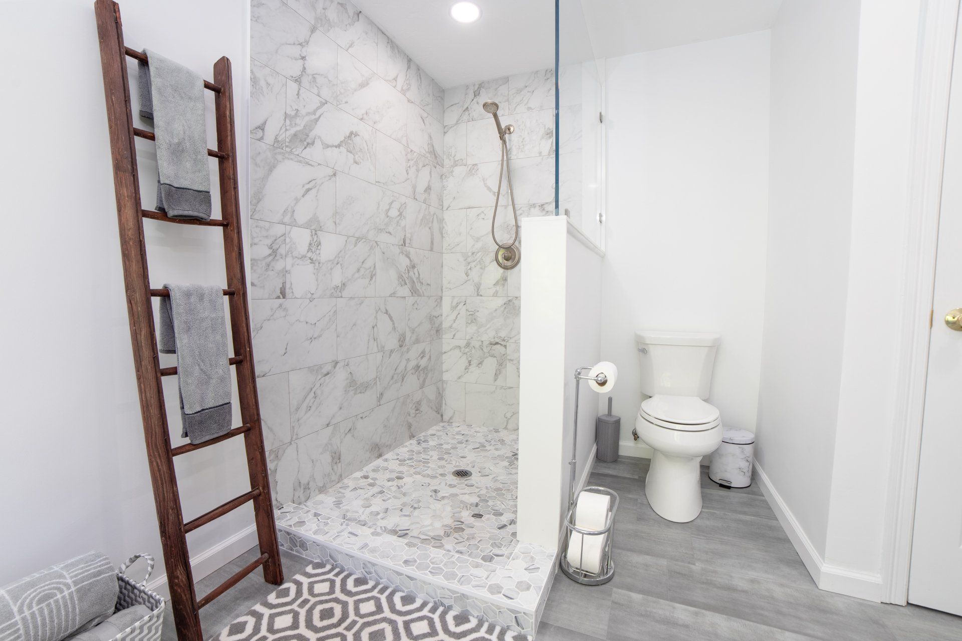 A bathroom with a walk in shower , toilet , and ladder.