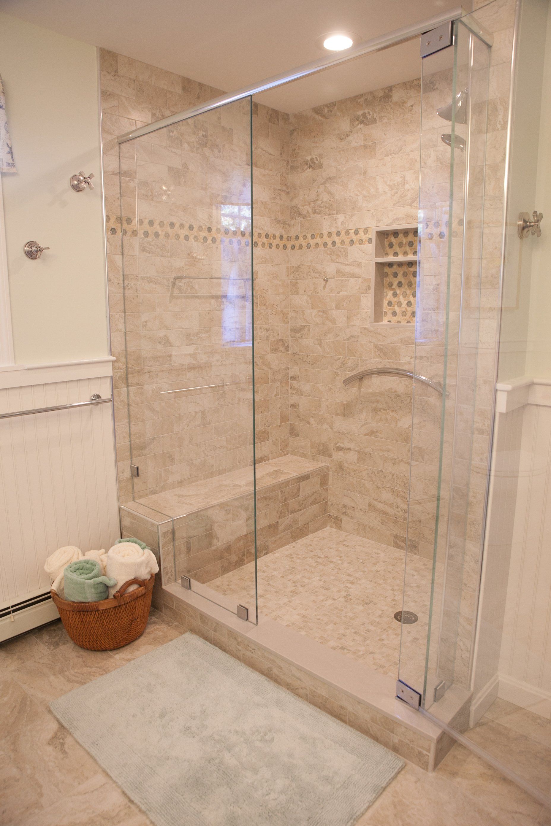 A bathroom with a walk in shower and a basket of towels.