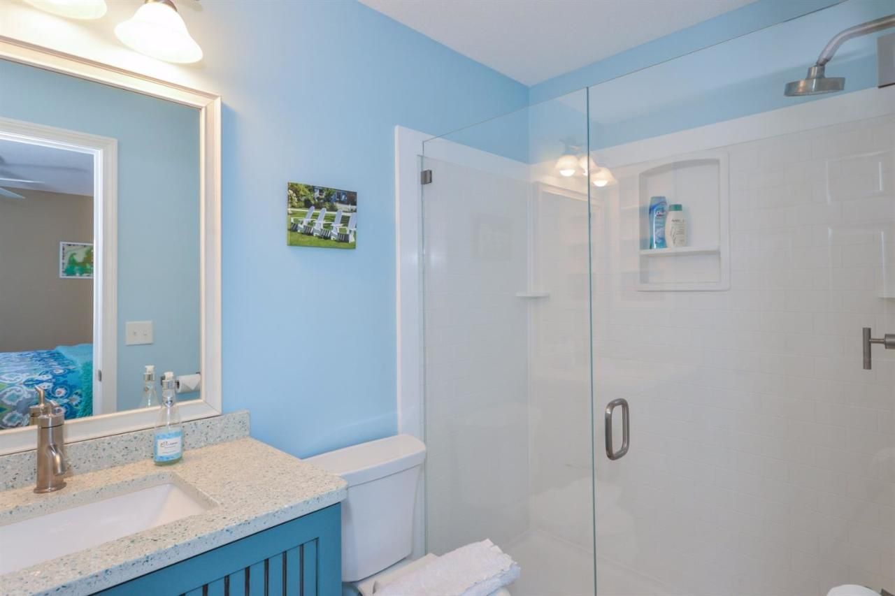 A bathroom with a toilet , sink , mirror and shower.