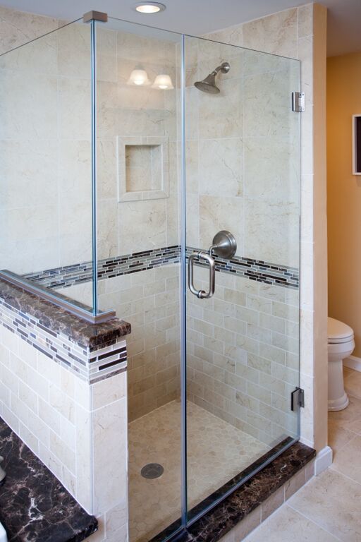 A bathroom with a walk in shower with a glass door