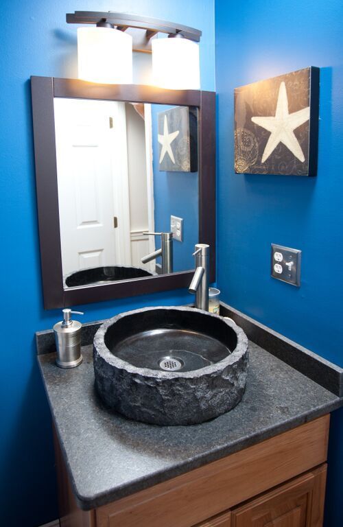A bathroom with blue walls and a sink and mirror