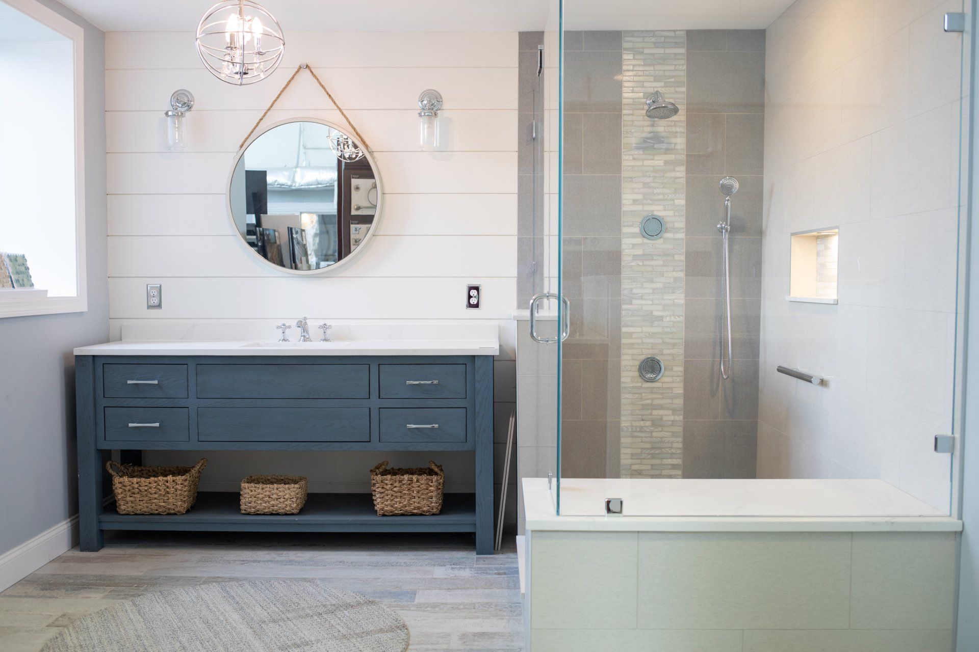 A bathroom with a walk in shower , sink , mirror and tub.