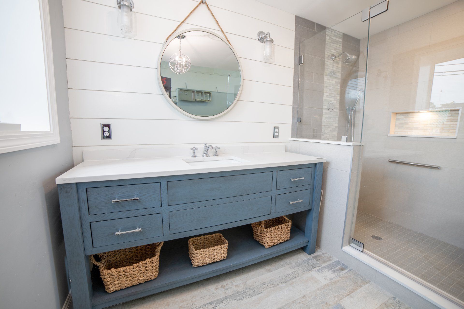A bathroom with two sinks , a mirror and a walk in shower.