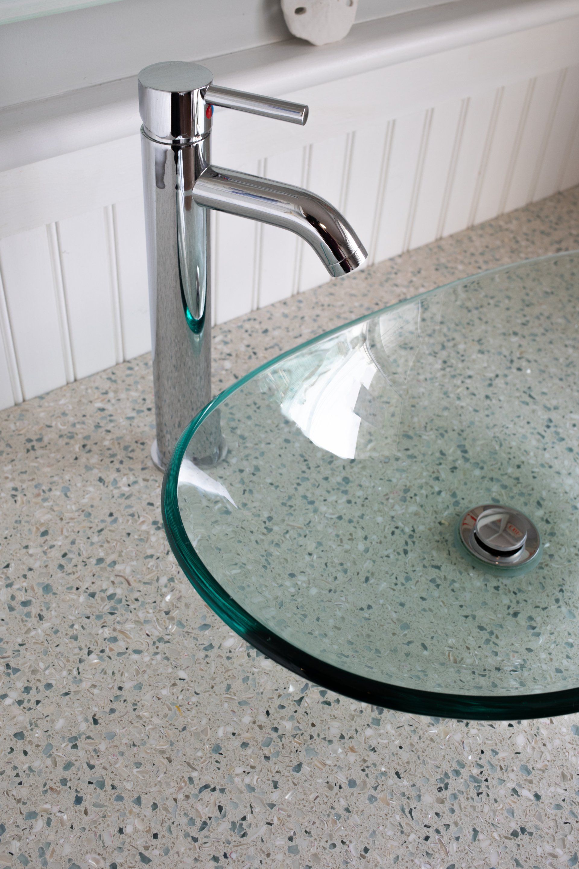 A bathroom sink with a clear glass bowl and a chrome faucet