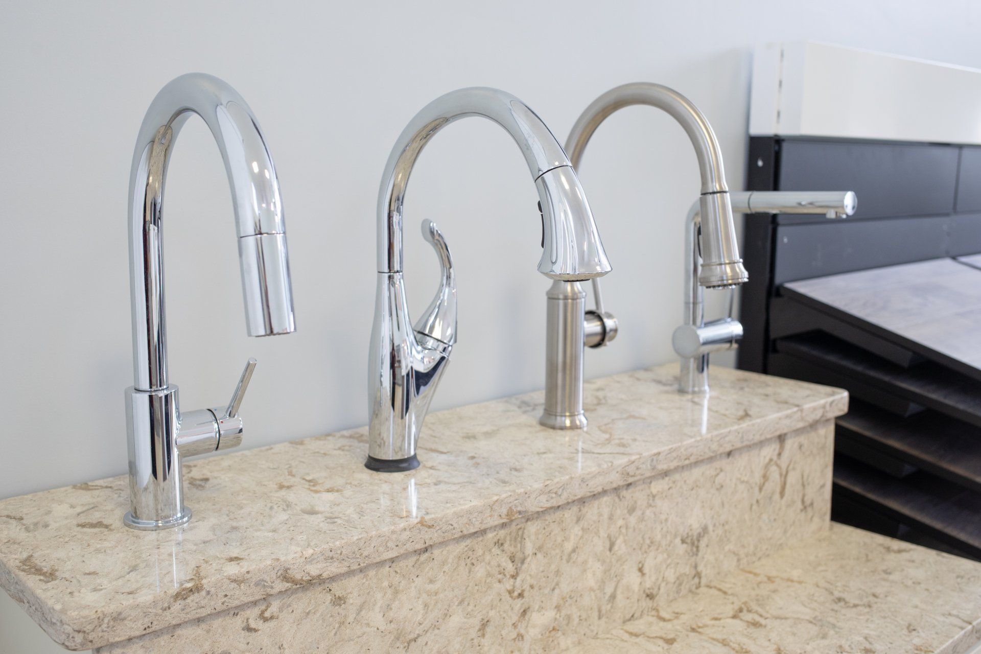 Three kitchen faucets are lined up on a counter top.