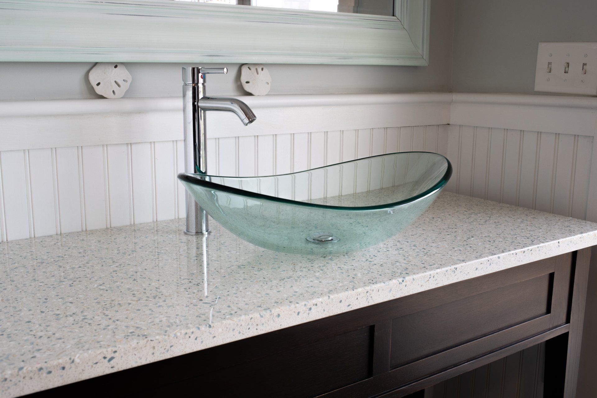 A bathroom with a glass sink and a mirror