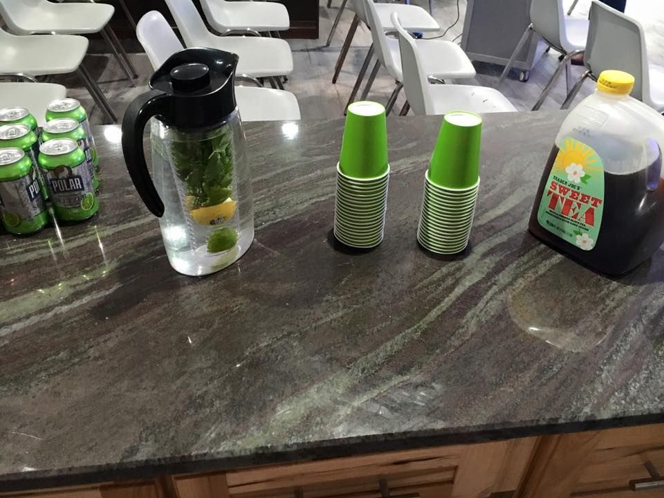 A bottle of iced tea sits on a counter next to a pitcher and cups