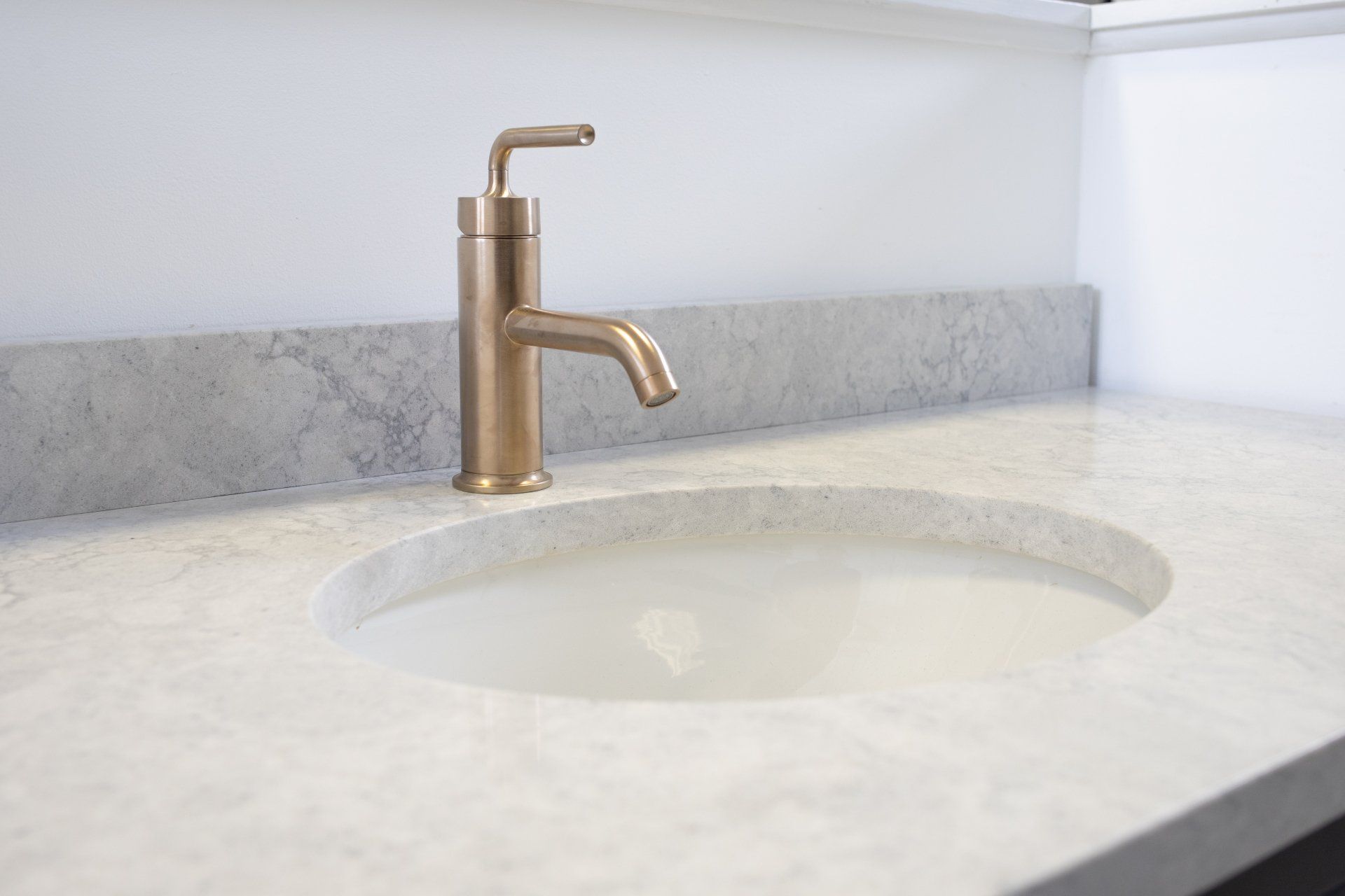 A bathroom sink with a brass faucet on a white counter top.