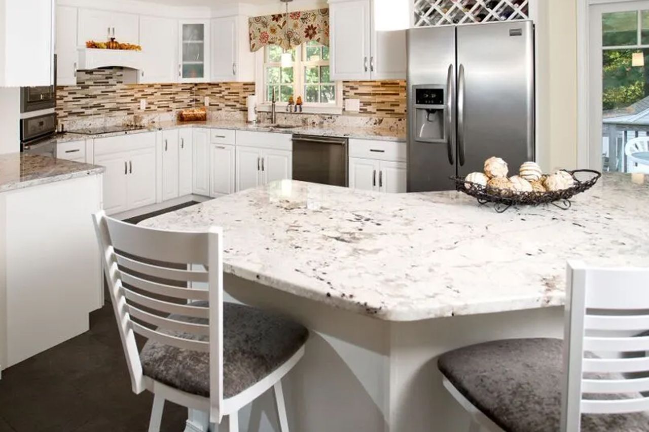 A kitchen with white cabinets, granite counter tops, stainless steel appliances and a stainless steel refrigerator.