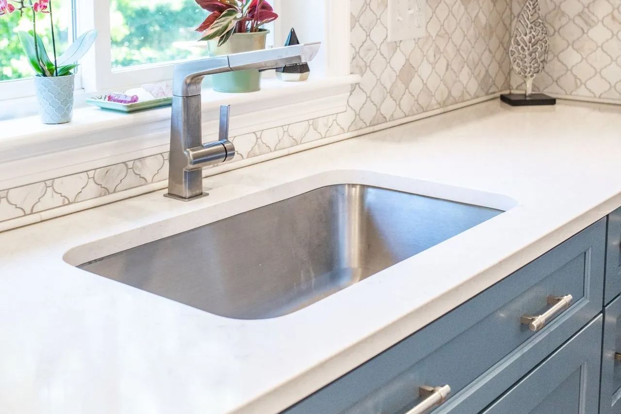 A kitchen sink with a faucet and a window in the background.