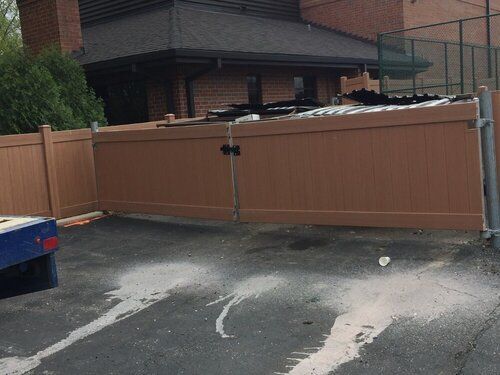 A wooden fence is sitting in a parking lot in front of a brick building.