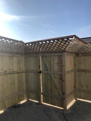 A wooden fence with a lattice roof and a gate.