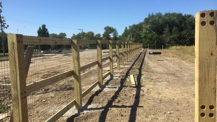 A wooden fence is being built on a dirt road.