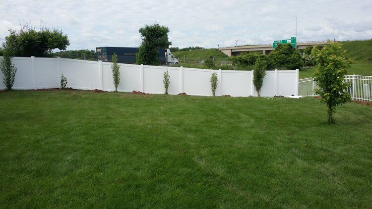A white fence surrounds a lush green lawn in a backyard.