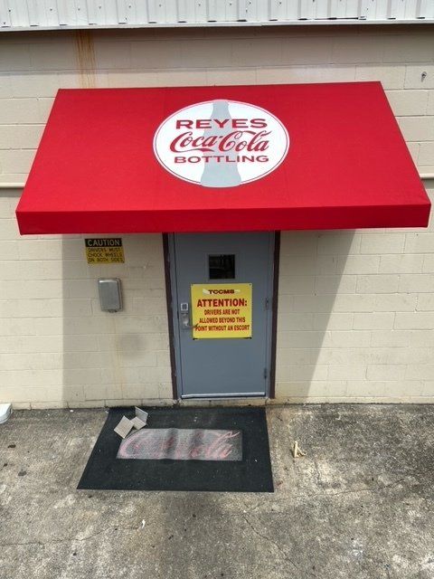 A red awning over a door that says reyes coca cola bottled