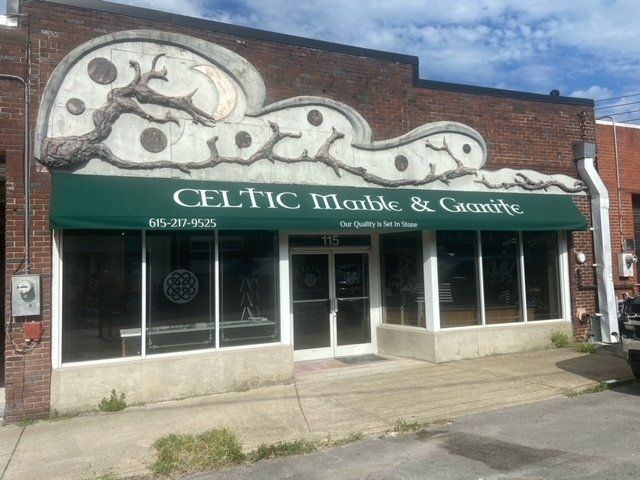 A store front with a green awning that says celtic marble & granite
