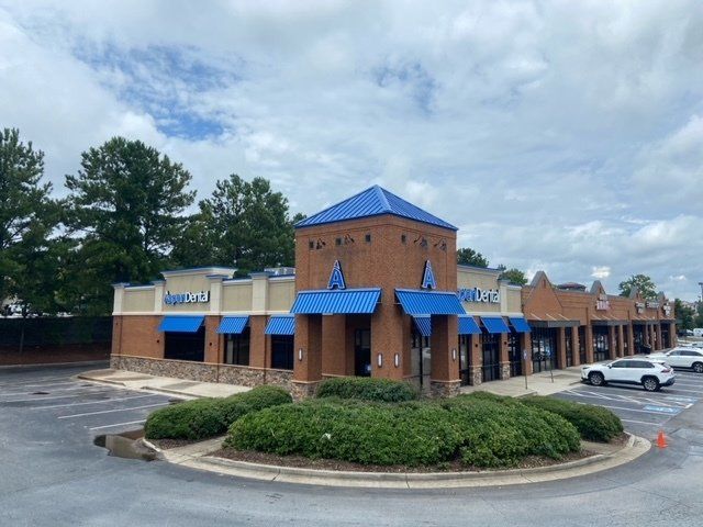 A brick building with blue awnings and a roundabout in front of it.