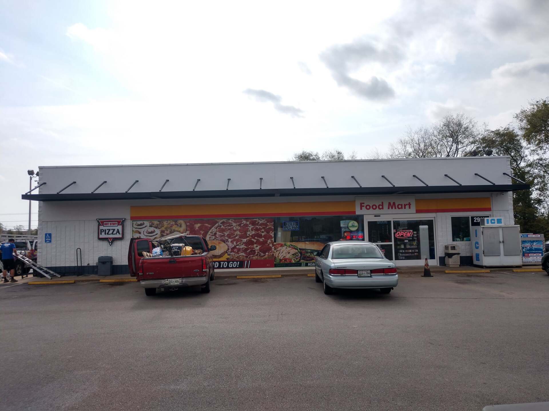 A red truck is parked in front of a food mart
