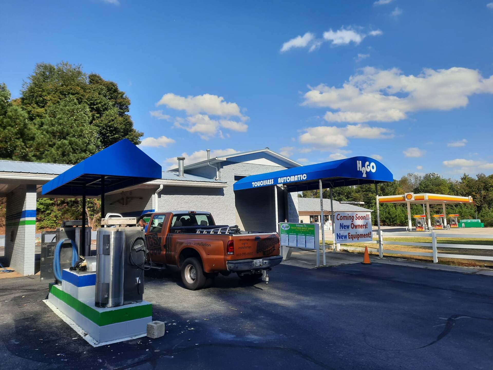 A truck is parked in front of a gas station with a blue awning.