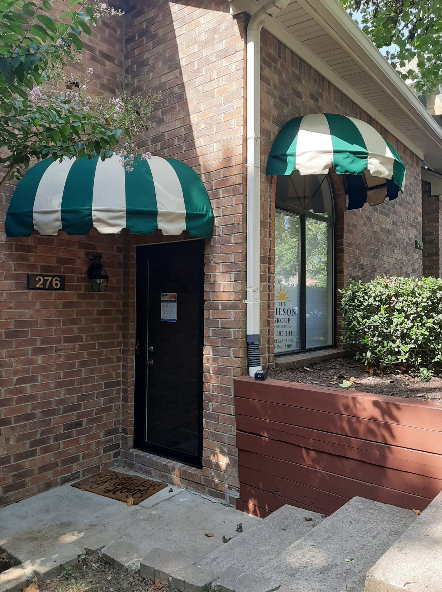 A brick house with a green and white awning over the door.