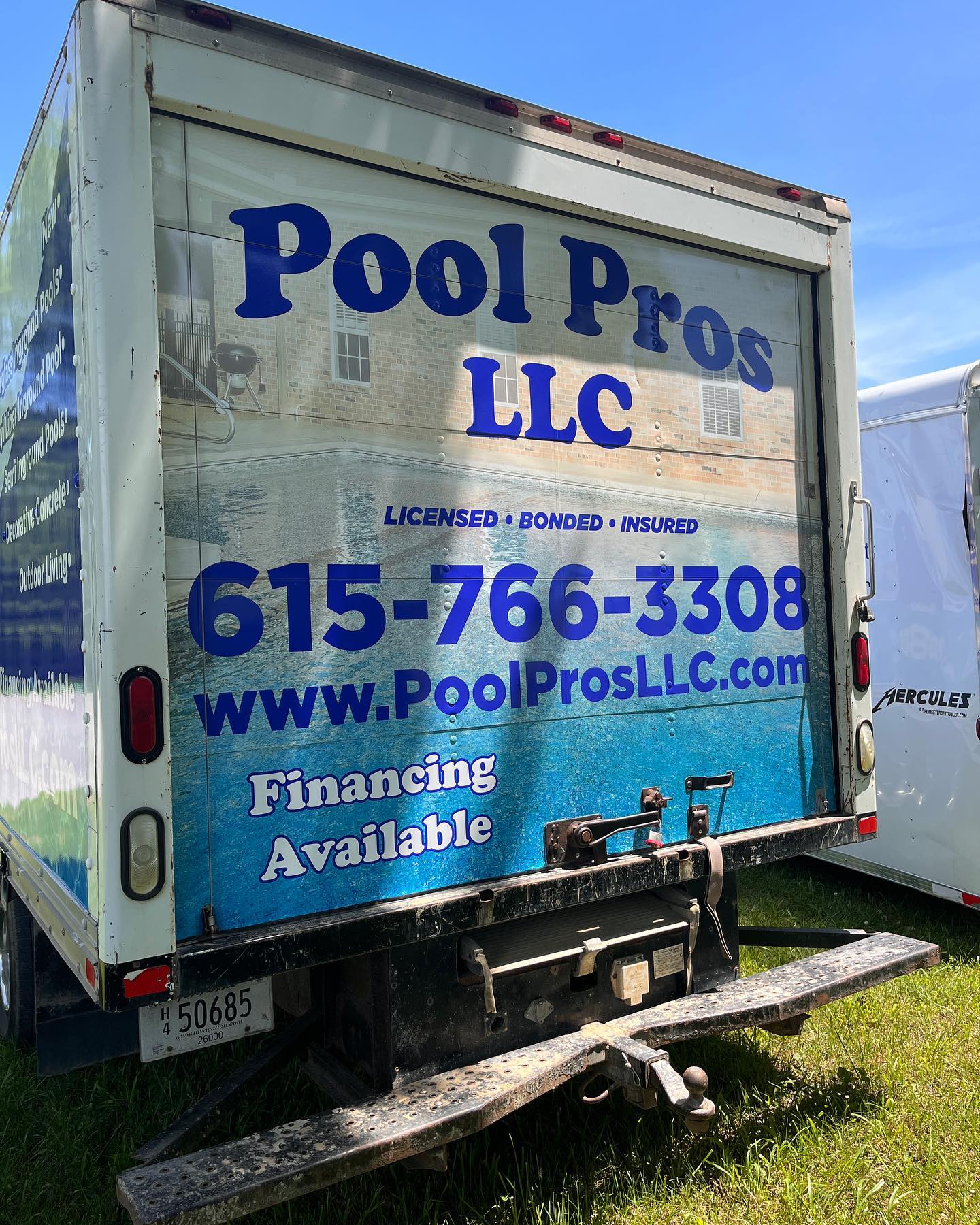 The back of a pool pros llc truck is sitting in the grass.
