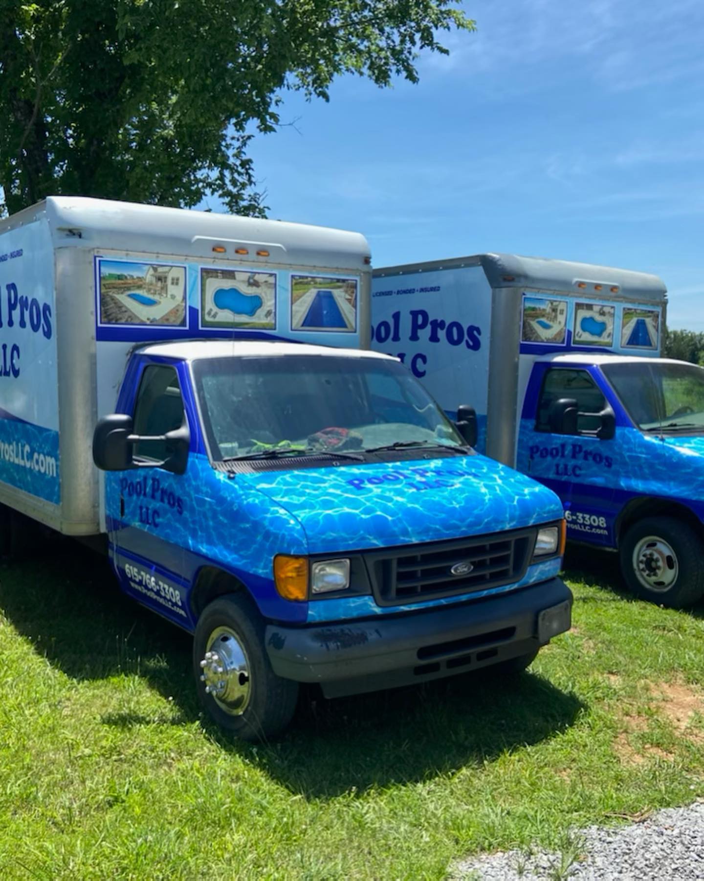 Two pool pros trucks are parked in the grass