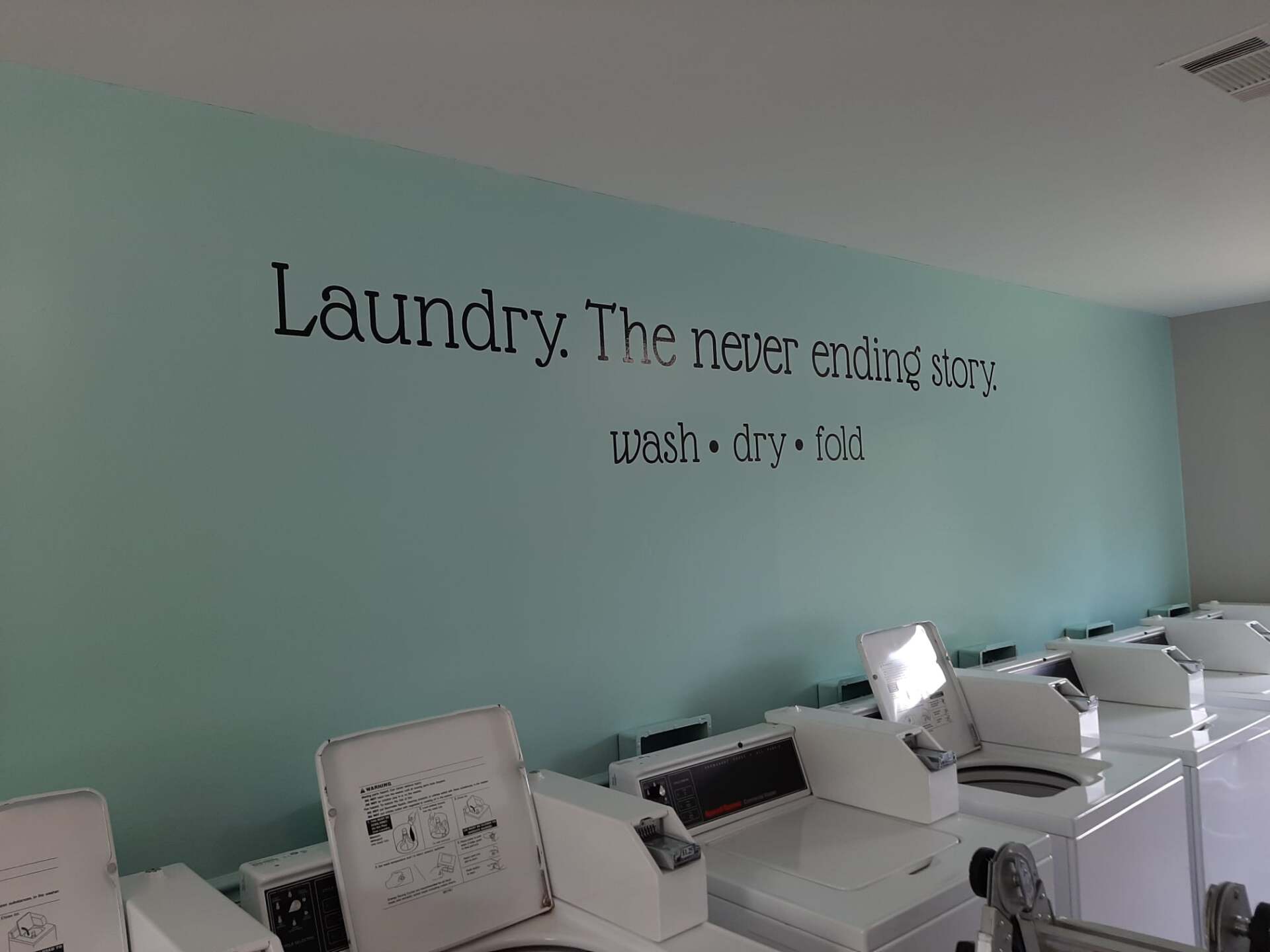 A laundry room with a sign that says laundry the never ending story