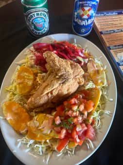 Plate of fried fish with sides, cabbage, salsa, and drinks.