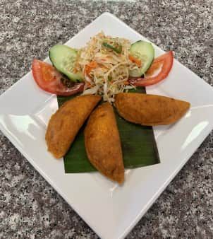 Plate with three fried pastries, salad, and tomato/cucumber slices.