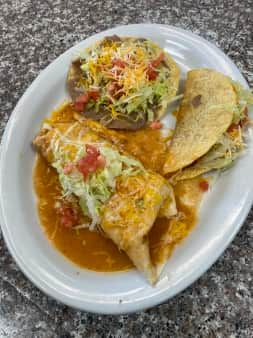 Plate with a burrito, tostada, and taco covered in sauce and toppings.