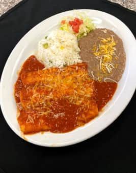Enchiladas with red sauce and cheese, served with rice, beans, and salad on a white plate.