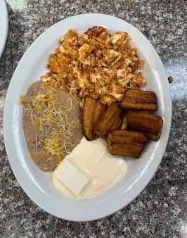 Plate of scrambled eggs, refried beans, fried plantains, cream, and butter.