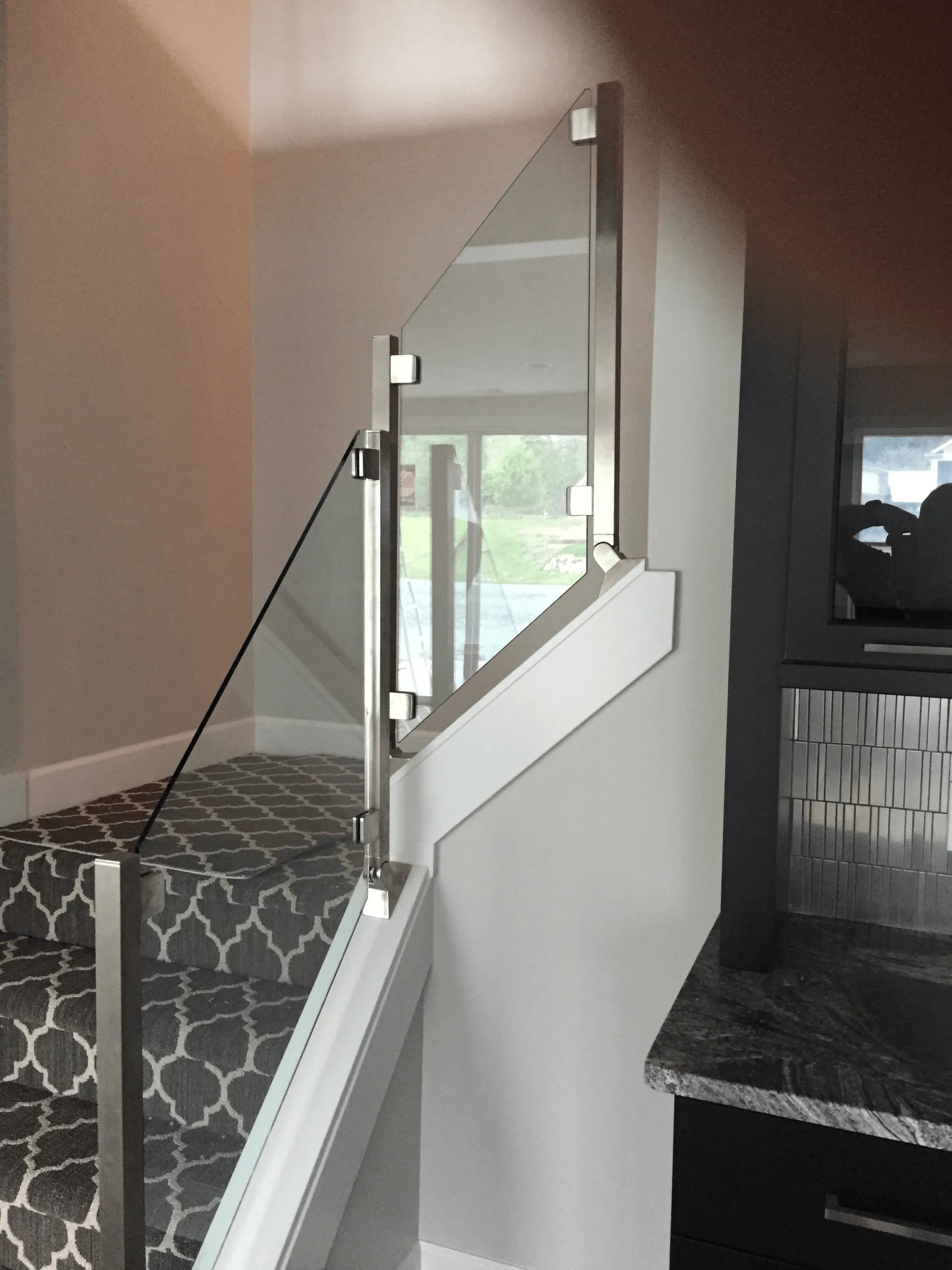 Glass stair railing with stainless steel posts, attached to a stairwell.