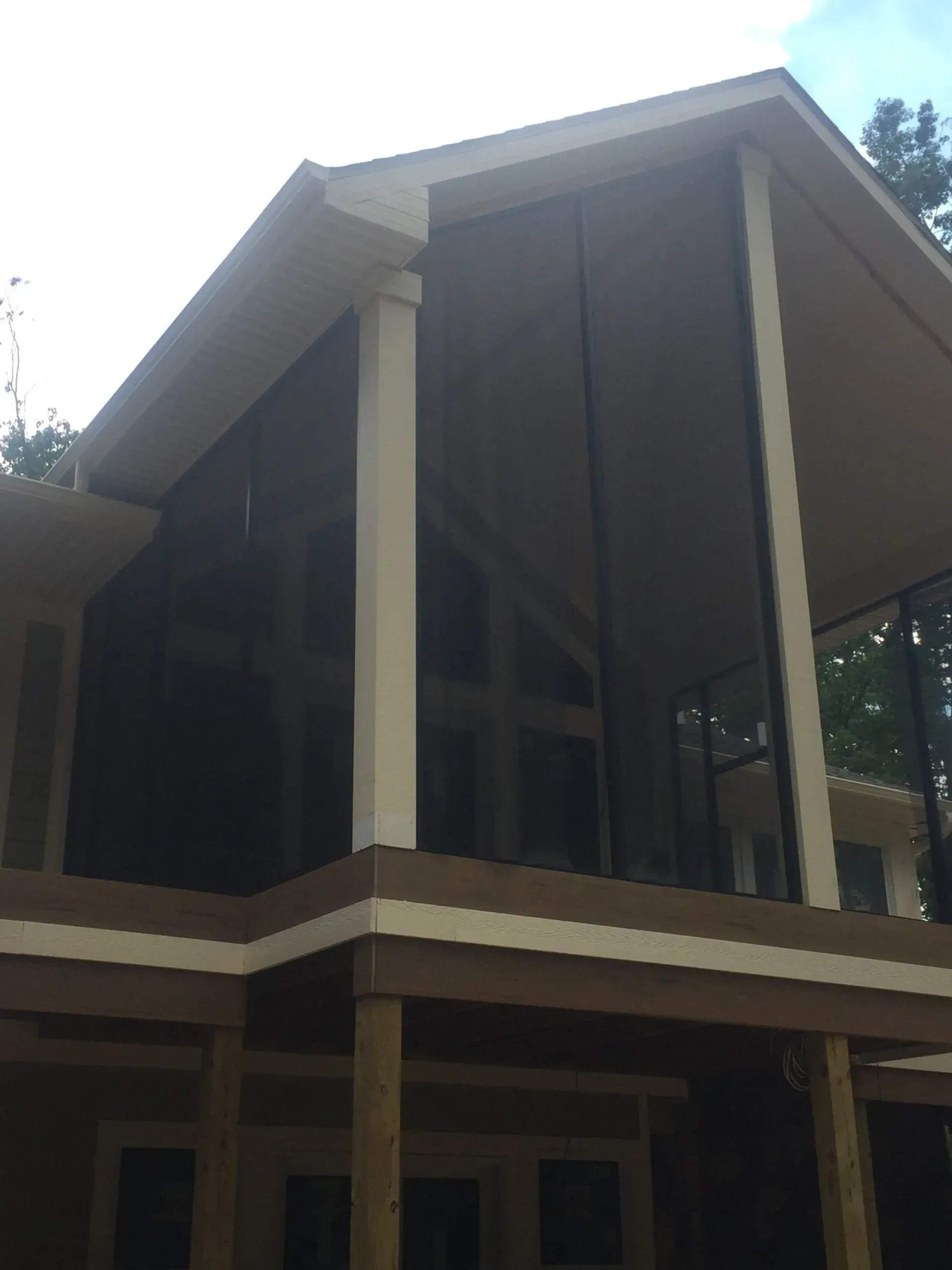Screened-in porch on a wooden deck, dark screens, white trim, with a pitched roof.