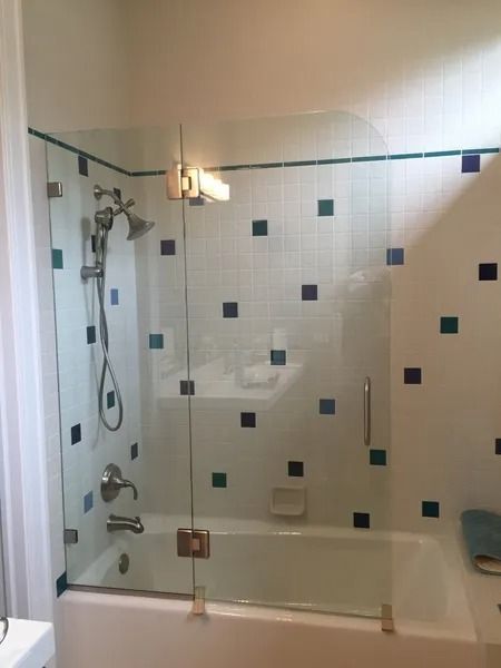 Glass shower enclosure in a bathroom with white and blue tiled walls.