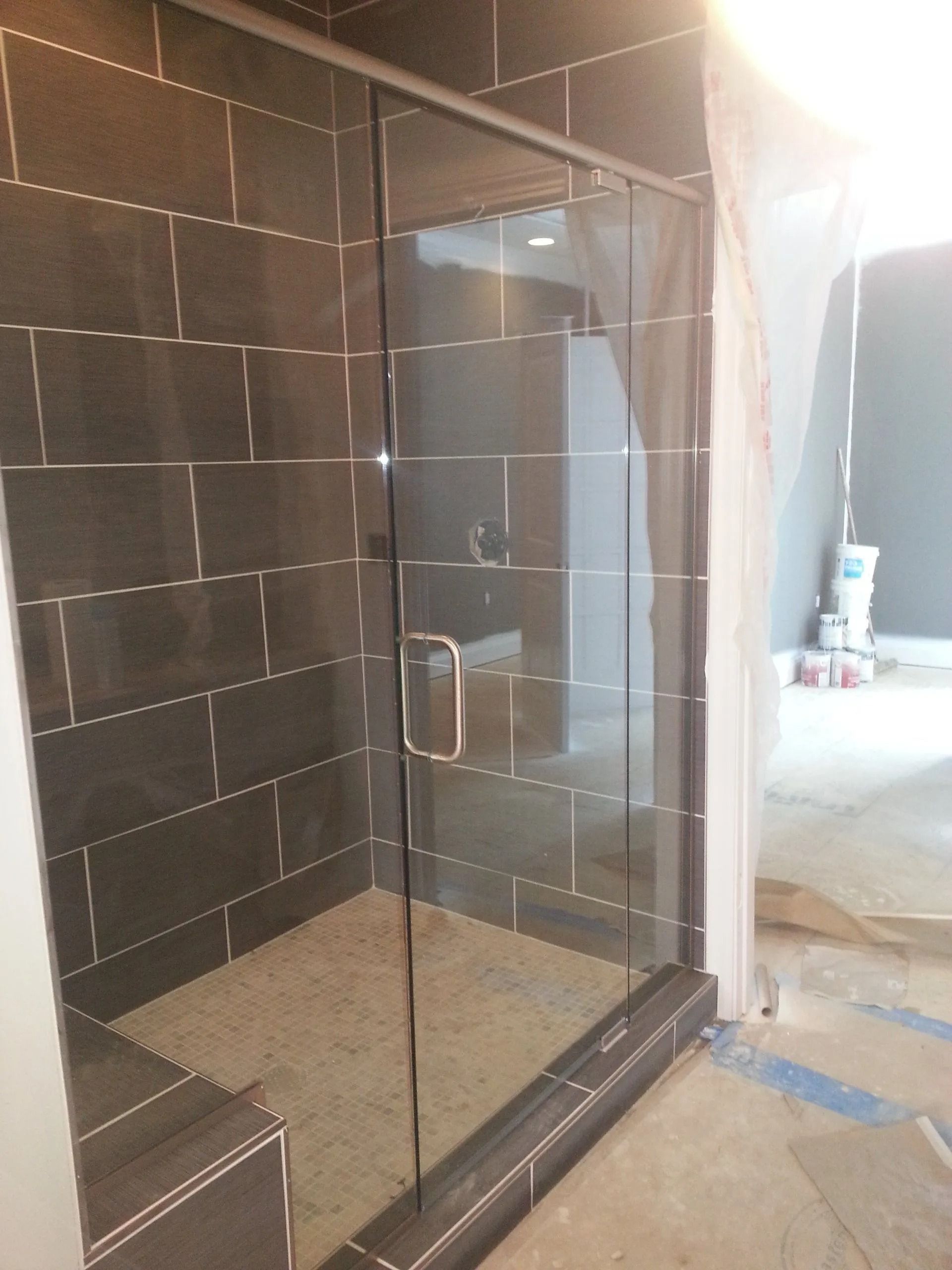 Glass shower enclosure with dark gray tile walls and light gray floor.