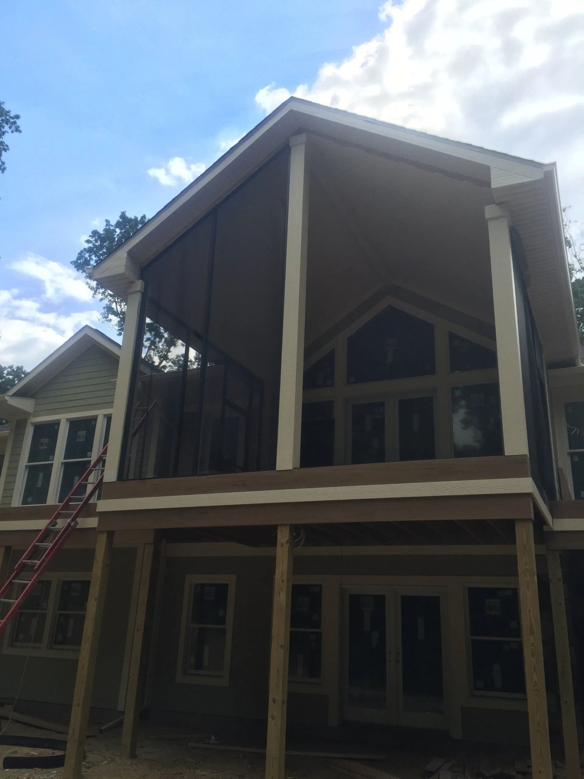 Screened-in porch on a house under construction; brown and beige tones; blue sky in the background.