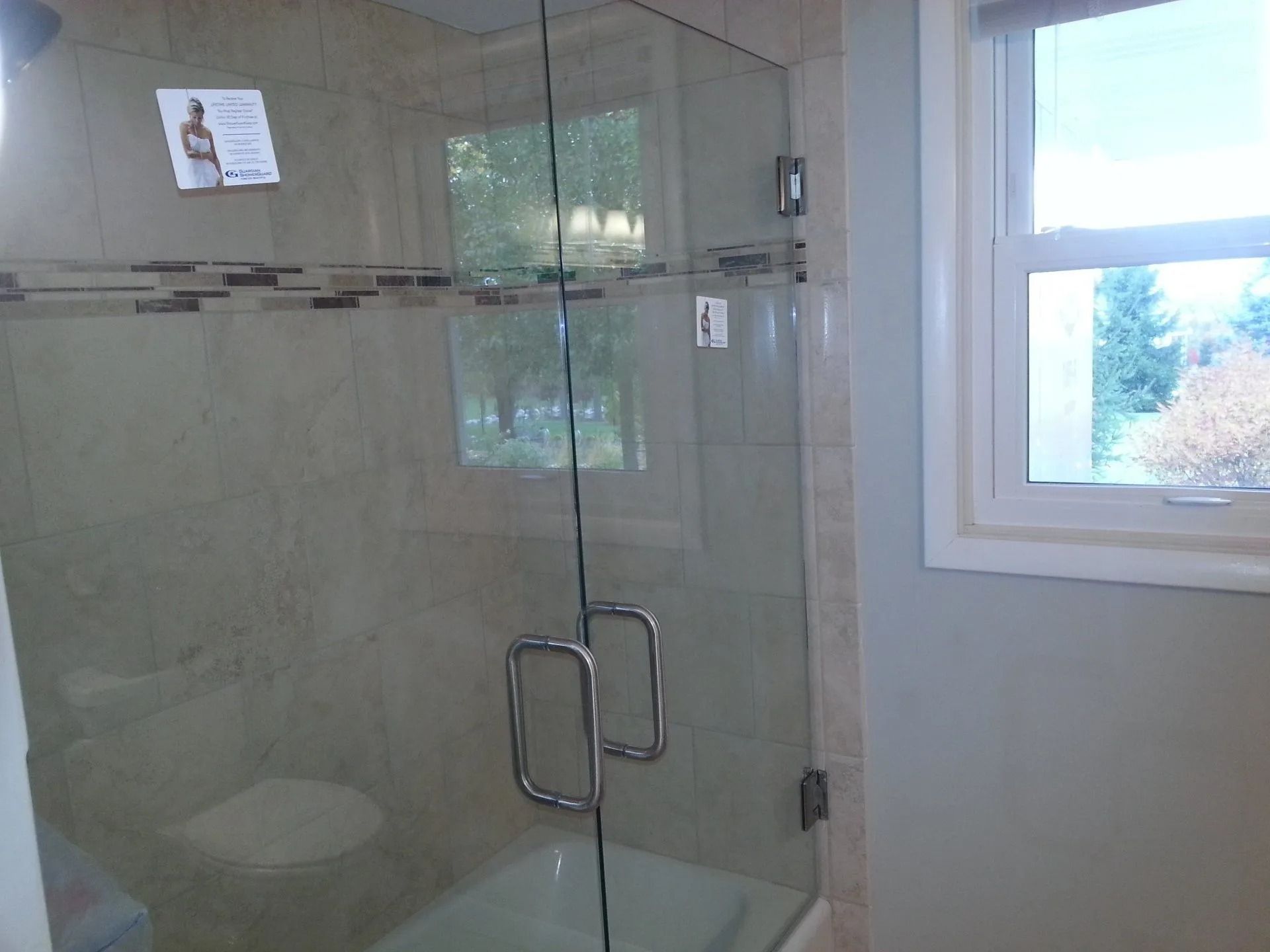 Glass shower enclosure in a bathroom with a window.