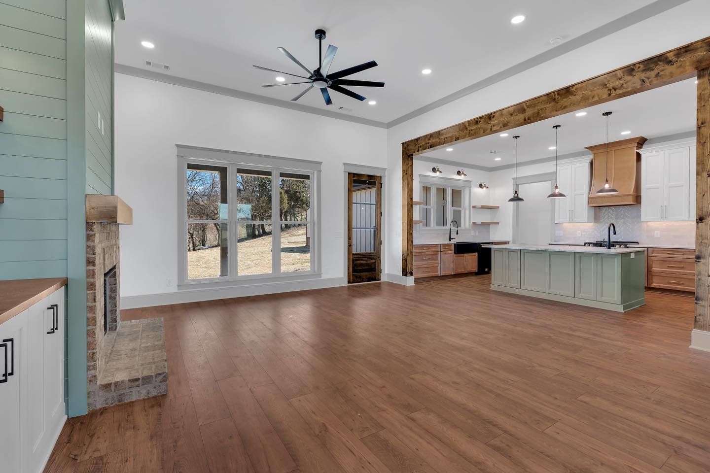 A large empty room with hardwood floors and a ceiling fan.