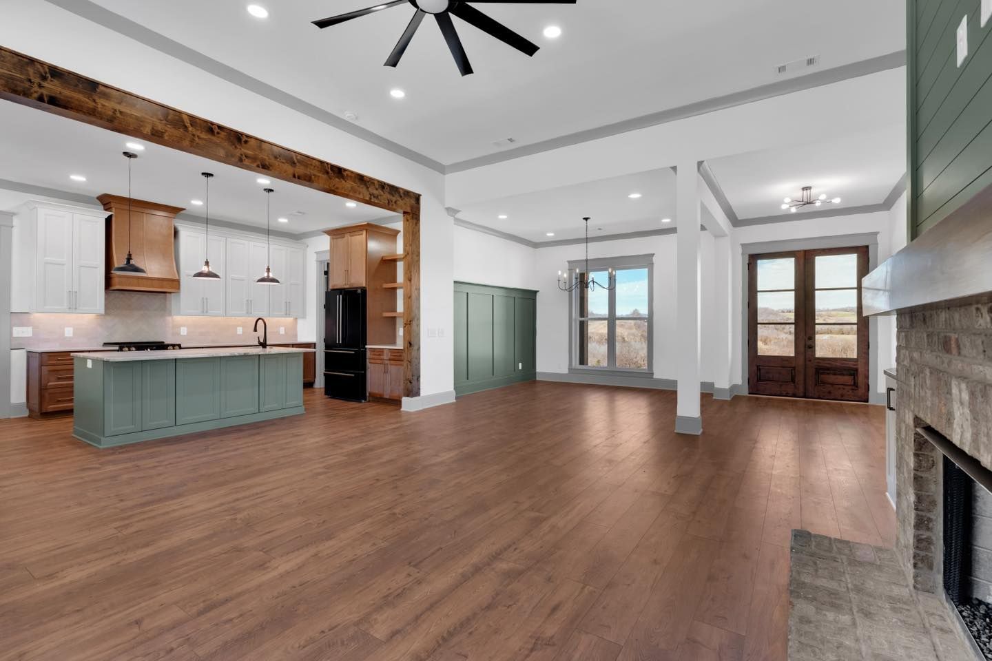 A large empty room with hardwood floors and a ceiling fan.